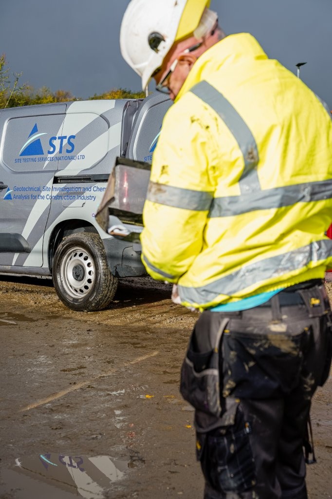 "Field technician in safety gear performing a CBR test on-site, with an STS-branded utility van in the background.
